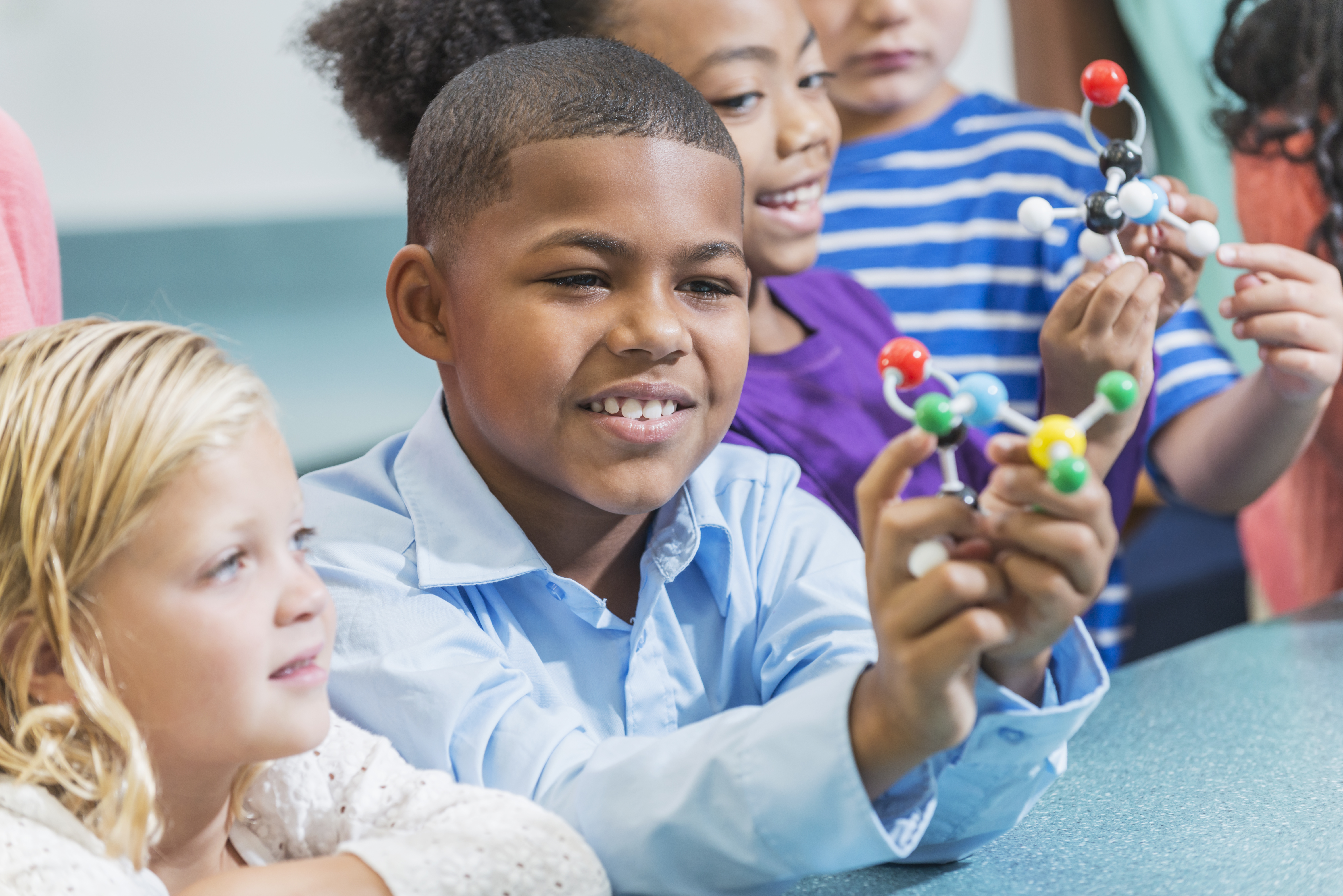 Multi-ethnic children in science class, focus on boy