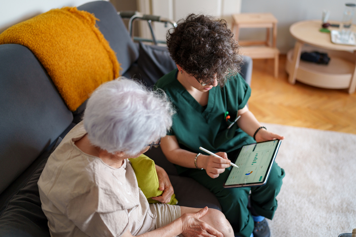 Caregiver and senior woman looking at a tablet together