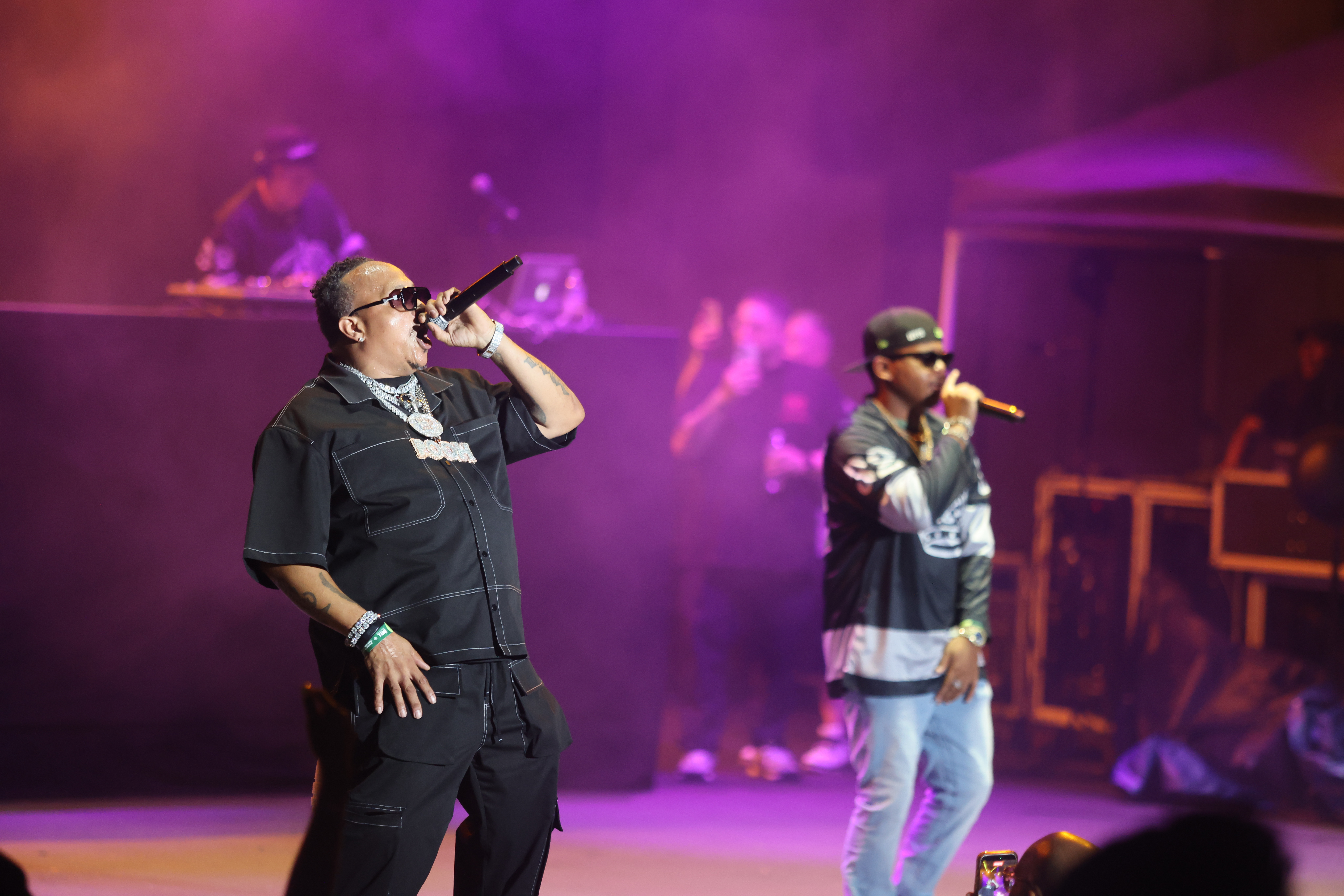 Two men performing on stage in a colorful, smoke-filled environment.