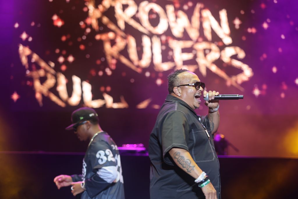 Two performers on stage, one holding a microphone and singing, with the text "Crown Rulers" displayed behind them.